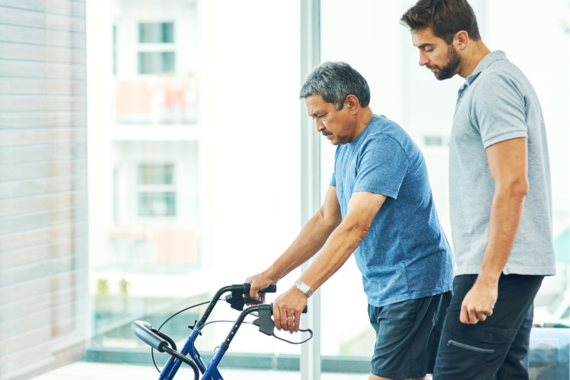 Pflegekraft kümmert sich um Mann am Rollator