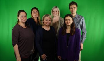 Fünf Frauen und ein Mann stehen vor einer Greenscreen-Wand