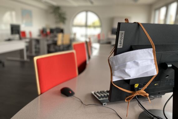 Mund-Nasen-Schutzmaske hängt über dem Desktop PC im Seminarraum im AFZ Rostock