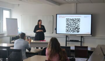 Dozentin steht vor interaktivem Whiteboard mit QR-Code