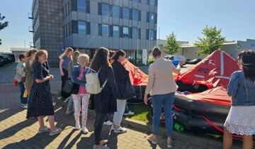Mitarbeitende des Jobcenters Rostock, der Bundesagentur für Arbeit und der Hafenwirtschaft bei der Besichtigung einer Rettungsinsel